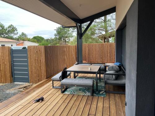 un patio avec une table et des chaises sur une terrasse dans l'établissement Montalivet maison neuve 1Km Plage, à Montalivet-les-Bains