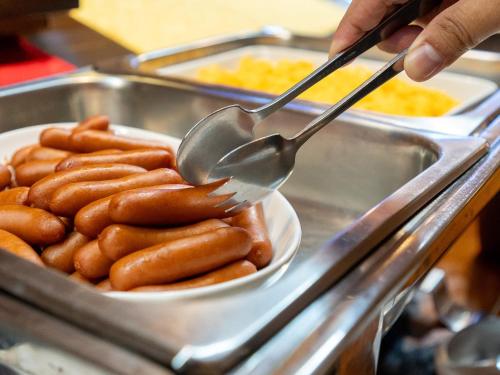 a person holding a spoon over a bowl of sausages at Hotel New Century in Okinawa City
