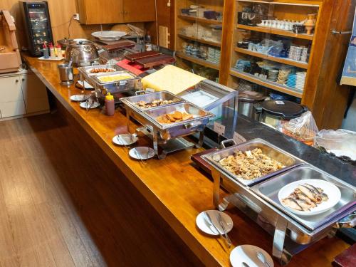 a kitchen with a counter with many trays of food at Hotel New Century in Okinawa City
