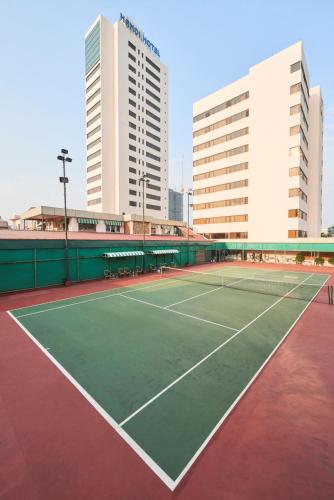 a tennis court with two tall buildings in the background at Hanoi Hotel in Hanoi