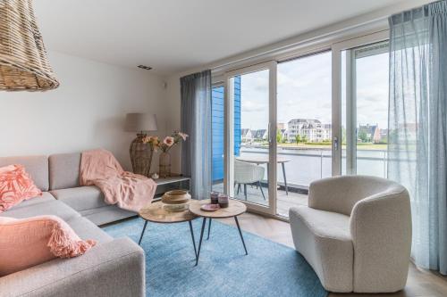 a living room with a couch and chairs and a balcony at The Boathouse Lodge in Harderwijk