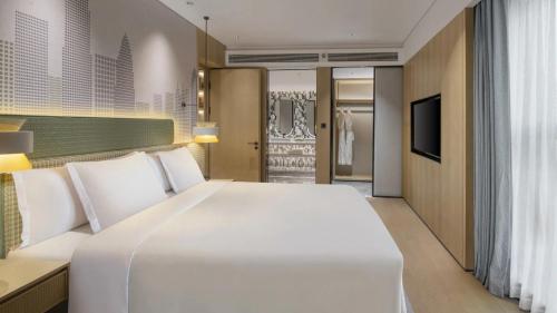 a bedroom with a large white bed and a television at Holiday Inn Shenzhen Nanshan by IHG in Shenzhen