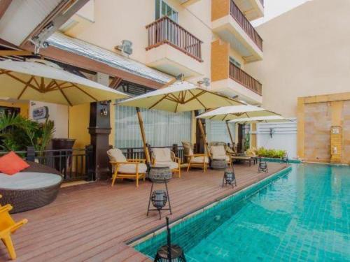 a pool with chairs and umbrellas next to a hotel at Sarita Chalet Beachfront Hotel in Jomtien Beach