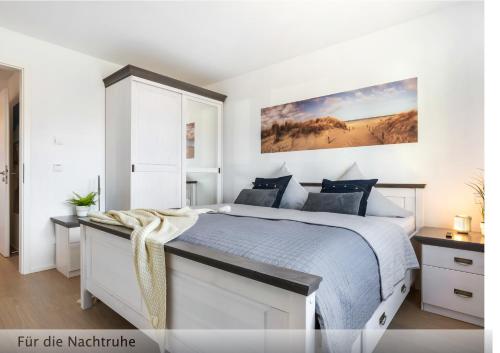 a white bedroom with a large bed with blue pillows at Der Küstengruß in Olpenitzdorf