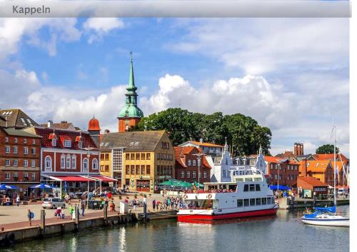 a boat is docked next to a harbor with buildings at Der Küstengruß in Olpenitzdorf