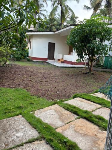 a white house with a tree in front of it at Angelina guest house, Anjuna Beach Road in Anjuna