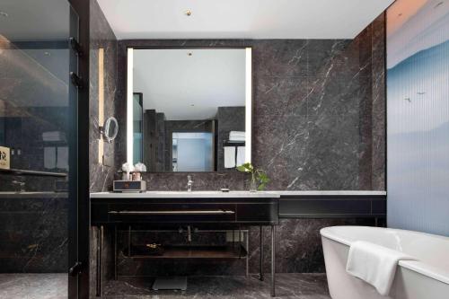 a bathroom with a large mirror and a tub at Wyndham Changzhou Liyang in Liyang