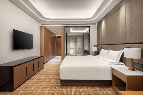 a bedroom with a large white bed and a flat screen tv at La Quinta by Wyndham Weifang South in Weifang