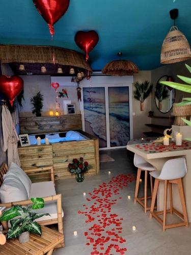 a room with a bed and a table with red hearts on the floor at Les Spas de la Mer, Appart&Spa Aloha, 100m de la plage, Plein cœur du Grau in Le Grau-du-Roi