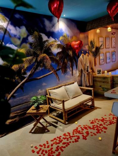 a room with a room with a palm tree and a couch at Les Spas de la Mer, Appart&Spa Aloha, 100m de la plage, Plein cœur du Grau in Le Grau-du-Roi