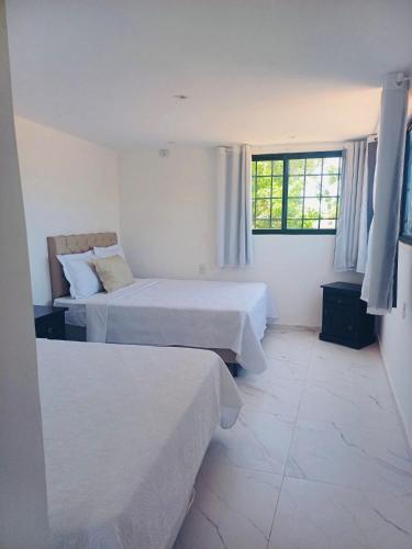 a hotel room with two beds and two windows at Residence Pipa Beach in Pipa