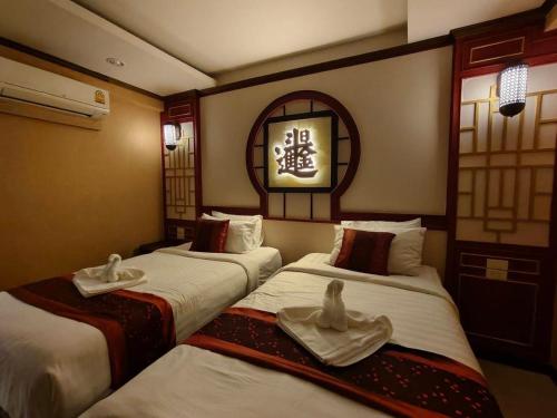 two beds in a hotel room with towels on them at The Boone Hotel in Chiang Mai