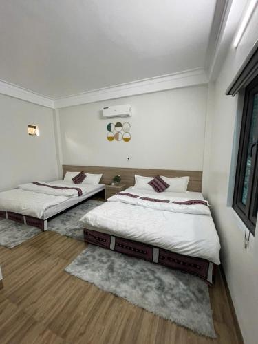two beds in a room with white walls and wood floors at Nhím Hotel MC - by BAY LUXURY in Mộc Châu