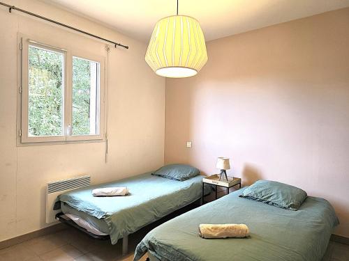 two beds in a room with a lamp and a window at Le Clos Andrée - Charmante maison 8 personnes - 5 lits - Climatisation réversible RDC - Parking 3 véhicules - Garage - Zone Nord Montauban - Terrasse et jardin in Montauban