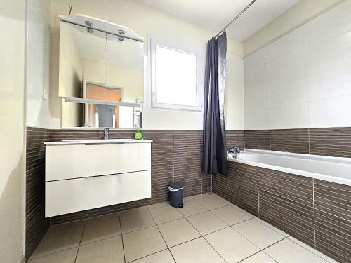 a bathroom with a sink and a tub and a mirror at Le Clos Andrée - Charmante maison 8 personnes - 5 lits - Climatisation réversible RDC - Parking 3 véhicules - Garage - Zone Nord Montauban - Terrasse et jardin in Montauban