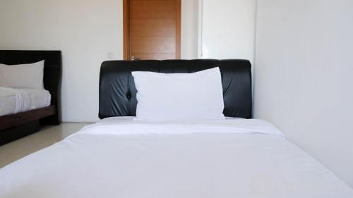 a bed with a white pillow on it in a room at Spacious 2BR with Access to Mall at Aryaduta Residence Surabaya Apartment By Travelio in Surabaya