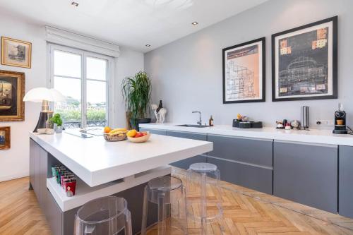une cuisine avec un grand comptoir blanc et des tabourets dans l'établissement Panorama - Magnificent flat with breathtaking view of Fourvière Basilica, à Lyon