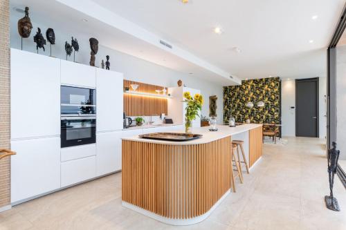 une cuisine avec des placards blancs et un îlot en bois au milieu dans l'établissement Futuriste - Exceptional residence with panoramic view, à Saint-Didier-au-Mont-dʼOr