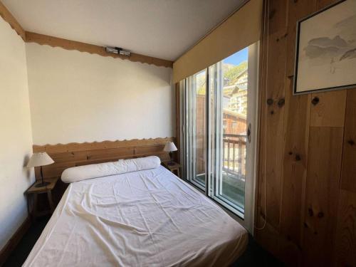 une chambre avec un lit et une grande fenêtre dans l'établissement Résidence Rochail - Duplex chaleureux en centre station avec vue sur les pistes MAE-5311, à Vénosc