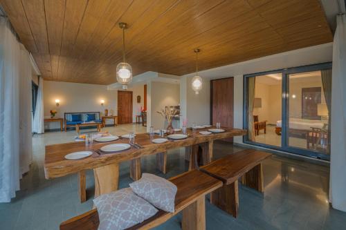 a dining room with a wooden table and a living room at SaffronStays Red Brick House, Panchgani - rustic villa with huge lawn and terrace in Panchgani