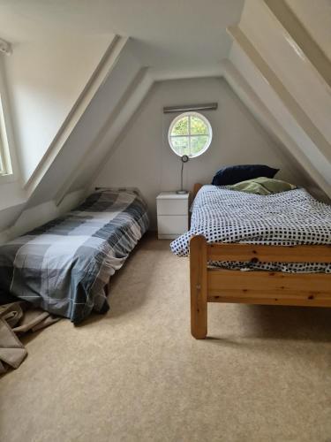 a attic bedroom with a bed and a window at Rustiek authentiek Bakhuisje in Rijsenburg