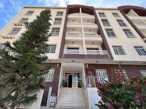 a large white building with stairs in front of it at Beautiful Salalah Beach Apartments - 1 by Beautiful Salalah Tours in Salalah