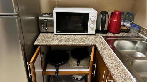 a kitchen counter with a microwave and a sink at Beautiful Salalah Beach Apartments - 1 by Beautiful Salalah Tours in Salalah