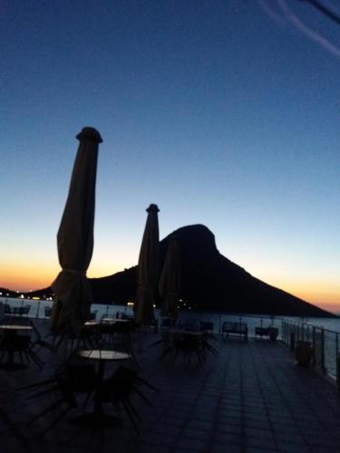 a group of chairs and umbrellas on a beach at sunset at MASSOURI BEACH HOTEL in Masouri