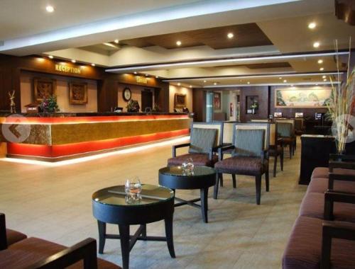 a lobby with tables and chairs and a bar at Sarita Chalet Beachfront Hotel in Jomtien Beach