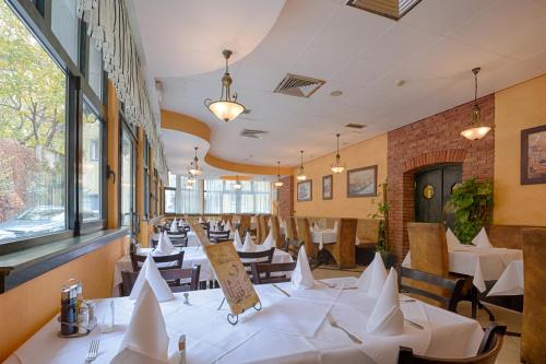 een restaurant met witte tafels, stoelen en ramen bij Belgrade City Hotel in Belgrado