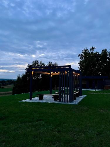 a pavilion in the middle of a grass field at Stodoła Na Kresach - widokowy domek drewniany, całoroczny JACUZZI & SAUNA in Bodzentyn