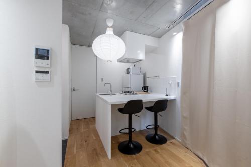 a kitchen with a white counter and two stools at trias 102 in Tokyo