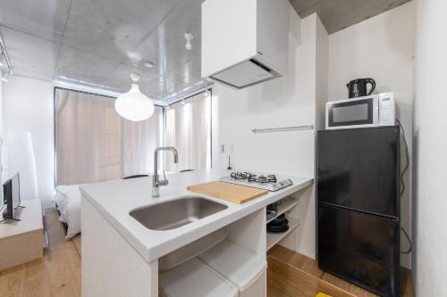 a kitchen with a sink and a black refrigerator at trias527 2-3 in Tokyo