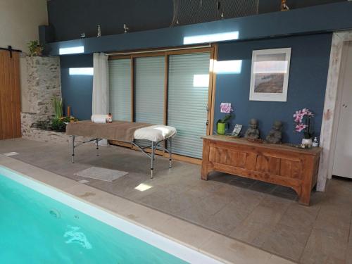 Cette chambre dispose d'une piscine et d'un lit à côté d'une table. dans l'établissement AU BOIS D'ORÉE, à Liré