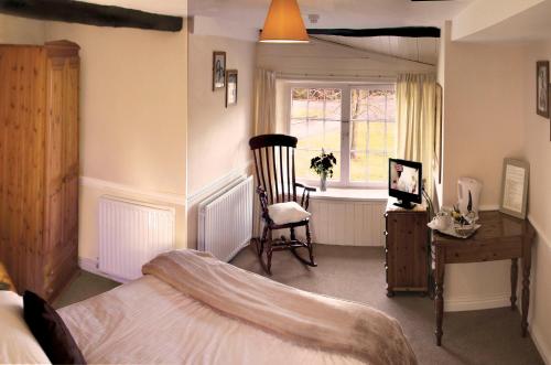 a bedroom with a bed and a chair and a window at Boot & Shoe Inn in Greystoke
