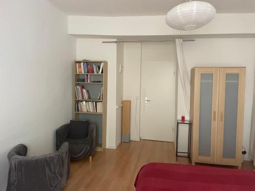 a living room with two chairs and a book shelf at Vaste chambre au centre ville, à 2 minutes du Lac in Neuchâtel