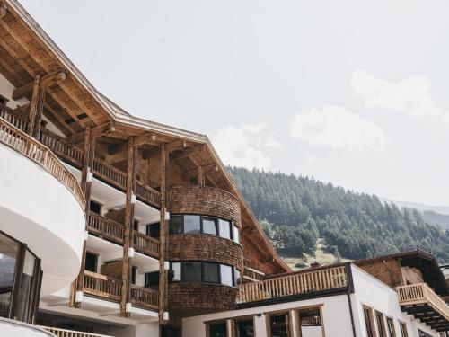 a building with a balcony with a mountain in the background at VAYA Nauders inklusive Summercard Basic in Nauders