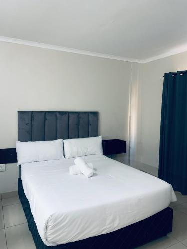 a bedroom with a large white bed with a blue curtain at Bayside Hotel Suites in Durban