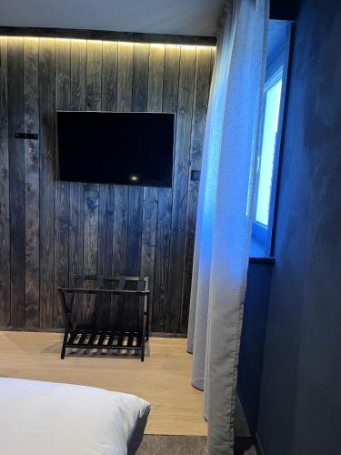 a bedroom with a tv on a wooden wall at B&B Leonie in Alveringem