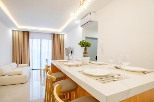 a white kitchen with a large white counter and chairs at Singgah House KLIA in Nilai