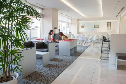 two women sitting at tables in a waiting room at Hotel Vista Sapporo Nakajima Koen in Sapporo