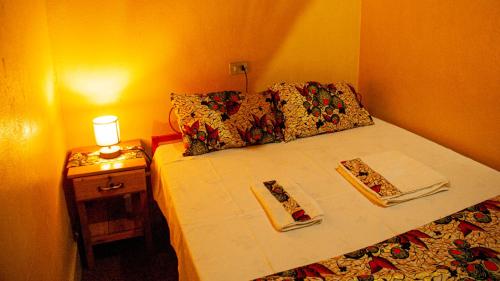 a bed with two napkins and a table with a lamp at Maison d'Accueil - Fondation San Filippo Neri in Bujumbura