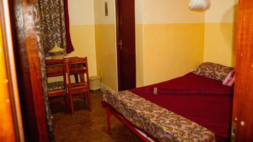 a small room with a bed and a table at Maison d'Accueil - Fondation San Filippo Neri in Bujumbura