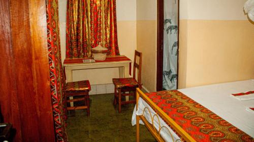 a room with a bed and two chairs and a table at Maison d'Accueil - Fondation San Filippo Neri in Bujumbura