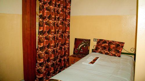 a bedroom with a bed with a curtain on the wall at Maison d'Accueil - Fondation San Filippo Neri in Bujumbura