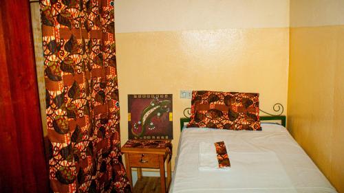a small bedroom with a bed and a curtain at Maison d'Accueil - Fondation San Filippo Neri in Bujumbura