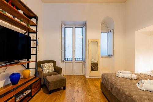 a living room with a bed and a chair and a television at La dimora del barone in Salerno