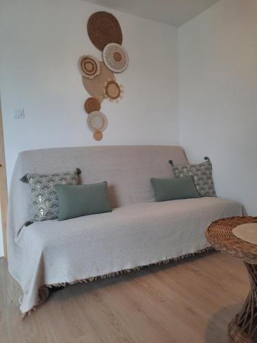 un canapé blanc avec des oreillers et des chapeaux sur le mur dans l'établissement Gîte de la Forêt de Poyant, à Lussant