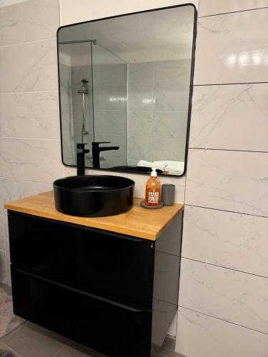 une salle de bain avec un lavabo noir et un miroir dans l'établissement T2 de la Bastide Rouge vue exceptionnelle (180°) sur Aix domaine privé T2 indépendant de 37 m2 avec terrasse exposée plein sud Piscine 10 X 5, à Aix-en-Provence