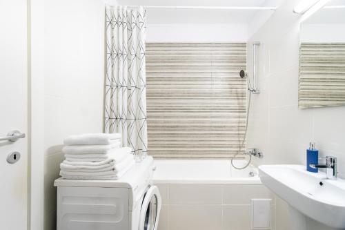 a white bathroom with a sink and a bath tub at Jasmine Luxury Aviatiei in Herăstrău
